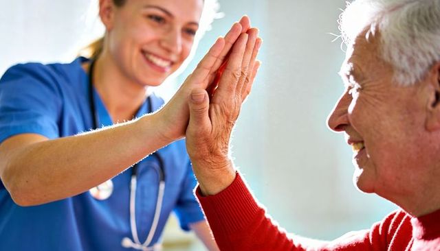Nurse high-fiving senior during care visit celebrating recovery and compassionate care