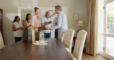 Family reunion with gift exchange around wooden table indoors
