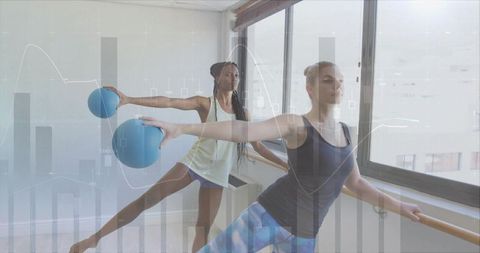 Women engaged in barre exercise holding blue balls