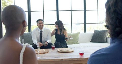 Smiling couple enjoying cocktail gathering with friends in bright modern living room