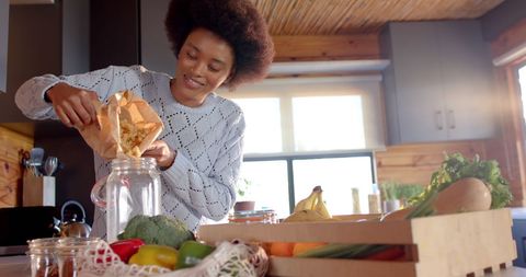 Smiling Woman in Cozy Kitchen Storing Pasta in Jar - Download Free Stock Images Pikwizard.com