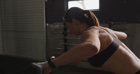 Athletic woman doing dumbbell lateral raises in gym for fitness training