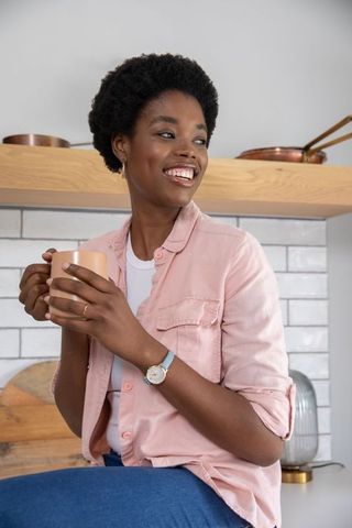 Smiling Woman Relaxing with Coffee in Modern Kitchen