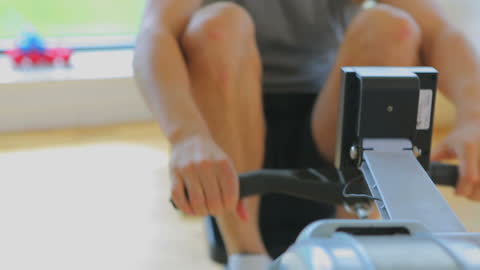 Man Exercising on Rowing Machine in Gym