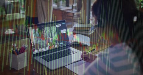 Teen girl studying at home with laptop and notebook, virtual data chart overlay