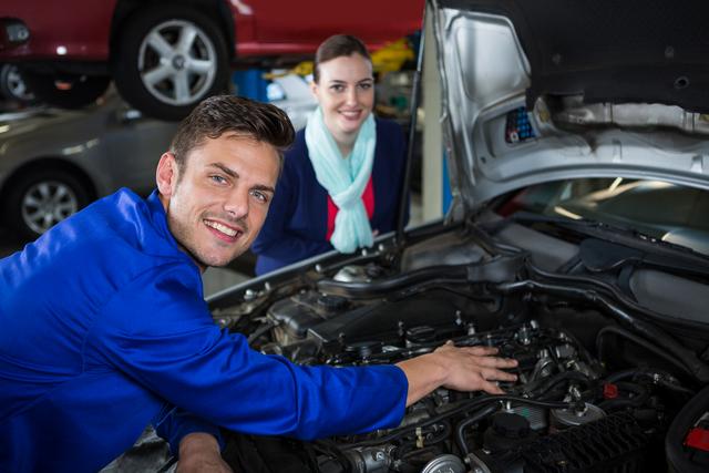 Mechanic showing customer the problem with car at repair garage