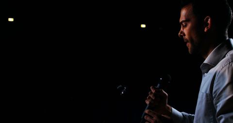 Young Man Holding Microphone on Dimly Lit Stage - Download Free Stock Images Pikwizard.com