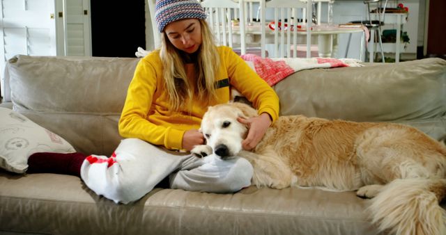 Happy caucasian female teenager petting her dog at home. Domestic life, pets, animals and care, unaltered.