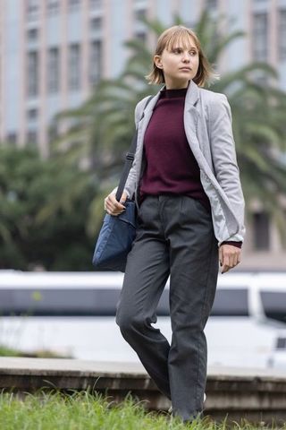 Walking confident professional wearing grey blazer and maroon sweater carrying navy bag