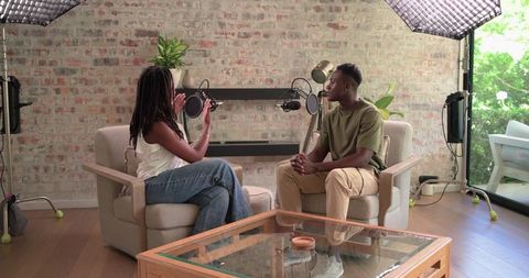 African american duo recording podcast in cozy brick home studio with soft lighting