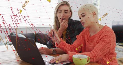 Two women collaborating on data analytics dashboards on laptop in home office