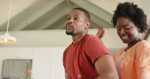 African american couple dancing playfully in sunlit kitchen, home romance moment