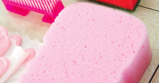 A pink sponge is featured prominently in the foreground, surrounded by cleaning supplies, with copy space. The arrangement suggests a focus on household chores or spring cleaning.