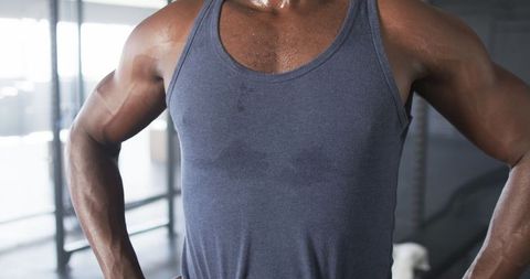 Athletic man sweating after intense gym workout in tank top