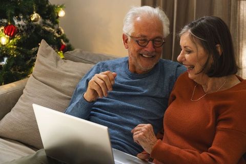 Senior couple enjoys christmas browsing on laptop at home