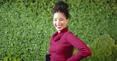 African American woman smiling and posing with tablet wearing maroon sweater and hoop earrings