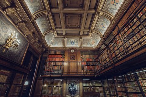 Grand traditional library with books, ornate wooden interior and bust