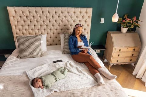 Mother relaxing and reading while newborn sleeping with animated sleep tracker overlay