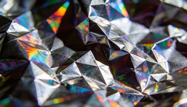 Crumpled holographic foil showing iridescent prismatic triangles and metallic reflections