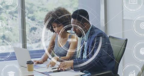 Collaborating colleagues reviewing documents with laptop and data visualization overlay