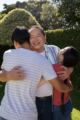 Asian Family Embracing Under Sunlit Garden Arch