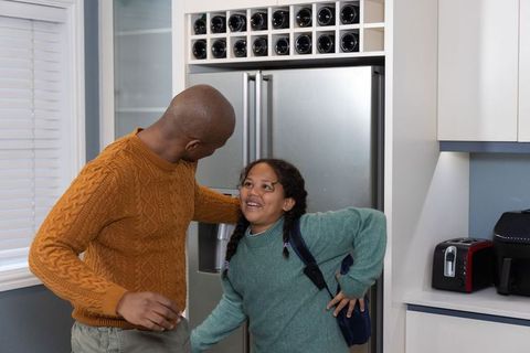 Dad greeting daughter at fridge in bright kitchen smiling bonding morning routine family