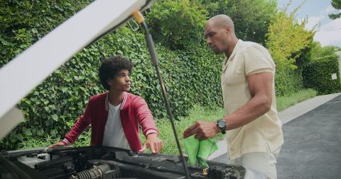 Father and son teamwork checking car engine in garden driveway