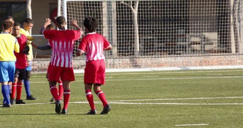 Youth soccer players celebrating on field showing teamwork