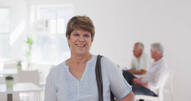 Smiling Woman in Bright Office Space with Colleagues in Background - Download Free Stock Images Pikwizard.com