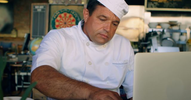 Chef using laptop in restaurant kitchen for recipe - Download Free Stock Images Pikwizard.com