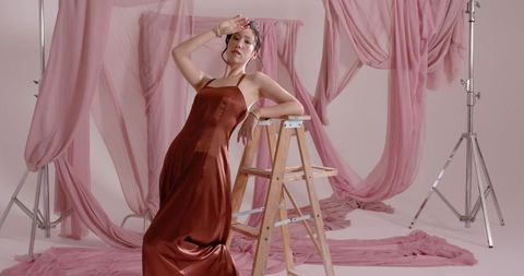 Elegant female model in fashion studio with flowing pink drapery