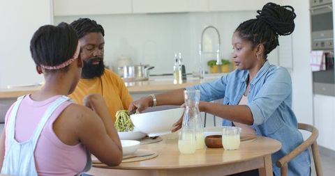 African american family sharing homemade pasta dinner in bright modern kitchen