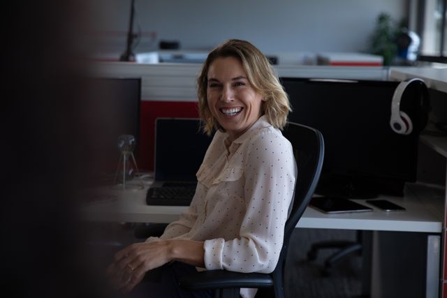 Smiling Businesswoman Sitting at Desk in Creative Office - Download Free Stock Images Pikwizard.com