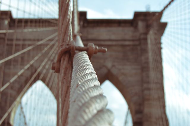 This photo showcasing the close-up of suspension cables along with historic architecture is ideal for illustrating engineering concepts, urban infrastructure, or architectural design. It emphasizes the texture and structure, making it appealing for educational resources, presentations on urban planning, or marketing materials for construction companies.