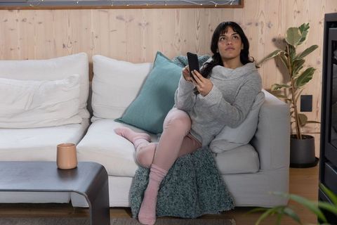 Woman Relaxing on Sofa with Smartphone in Cozy Interior