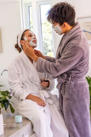 Couple applying face masks in bathrobes sharing relaxing morning skincare ritual