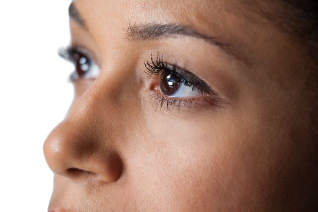 Close-up of womans eye and nose against white background