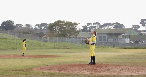 Confident female softball players exercising team spirit on field