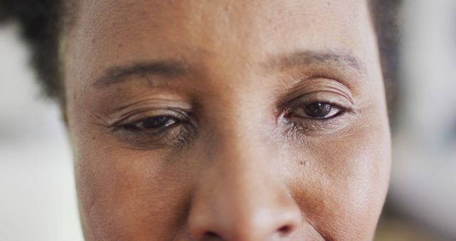 Closeup revealing facial expressions of an African American woman, with one eye closed and the other partially open. Can be used to depict human emotions, focus on relaxation, or attention to facial detail. Suitable for health, wellness, and beauty related themes.