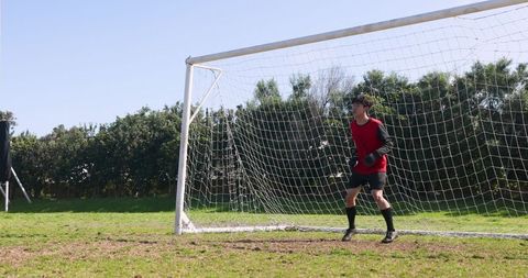 Asian Goalkeeper Standing Alert at Soccer Goal During Training