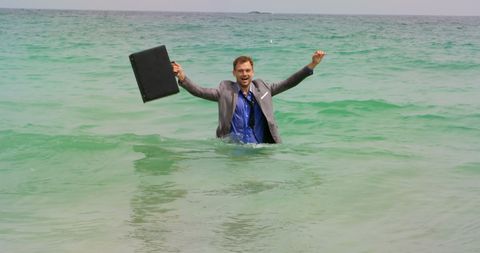 Businessman Celebrating Success Standing in Ocean Waves