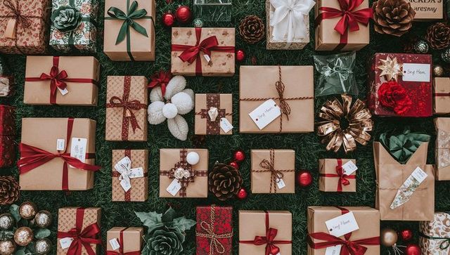 Rustic kraft gift flatlay on green foliage with red ribbons, pinecones and festive baubles