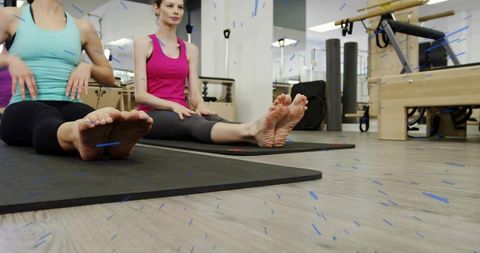 Two Women Stretching on Pilates Mats in Studio Practicing Flexibility and Core Mat Workout