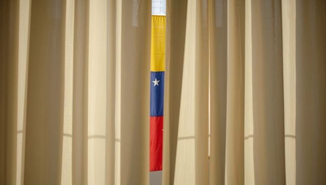 Parting beige curtains revealing vertical yellow blue red flag strip backlit minimalist symmetry
