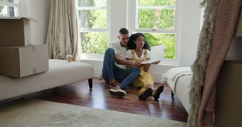 Happy Couple Using Laptop in Sunlit Room after Moving into New Home