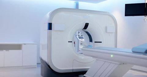 Modern ct scanner gantry with motorized patient table and blue pad in radiology suite