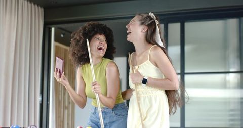 Diverse female friends laughing and playing pool in bright modern game room holding cues