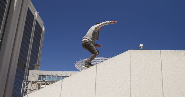 Caucasian male free runner landing on sloped concrete wall in sunny modern city, copy space - Download Free Stock Photos Pikwizard.com