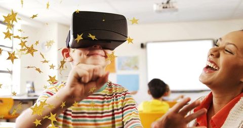 Student using virtual reality goggles while teacher laughing in interactive classroom
