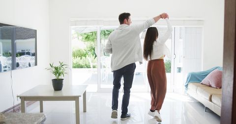 Joyful Couple Dancing in Sunny Living Room Celebrating Togetherness